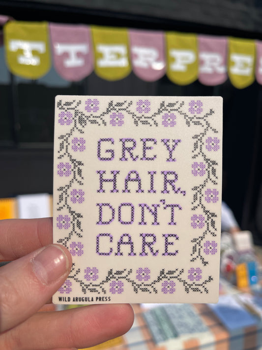 Sticker with 'Grey Hair Don't Care' text in a cross-stitch style