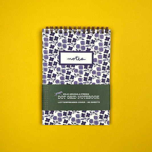 Notebook with floral pattern and 'notes' label on a yellow background